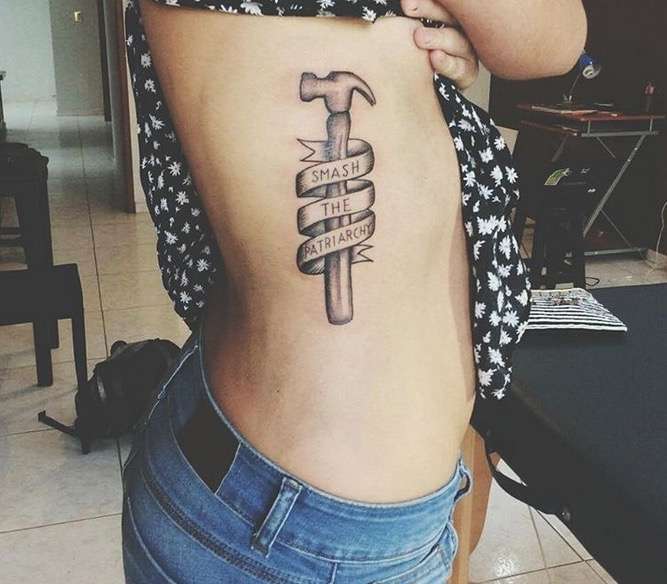 Tatuaje feminista de un martillo con una leyenda 