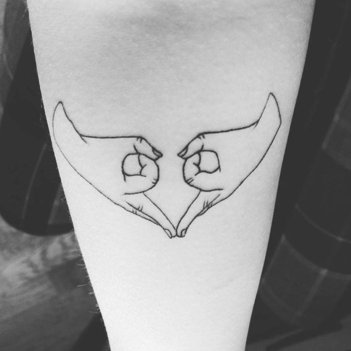 Tatuaje feminista de unas manos haciendo un corazón 