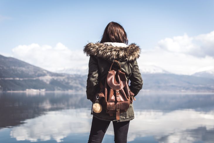 chica con mochila en un lago