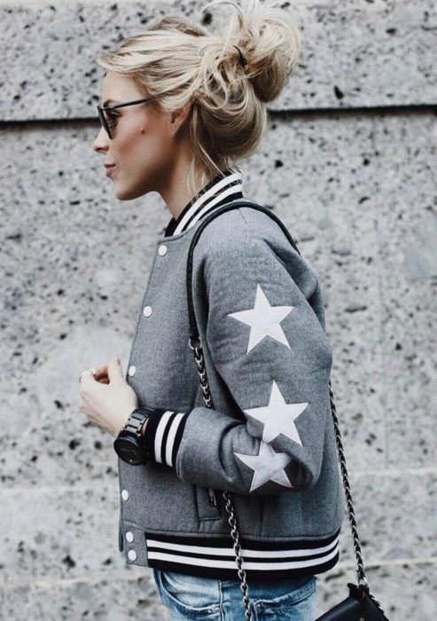 Chica usando una bomber jacket gris con estrellas 