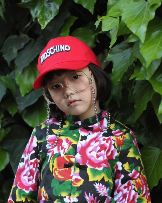 Niña de 6 años vistiendo gorra, gafas y blusa con flores 