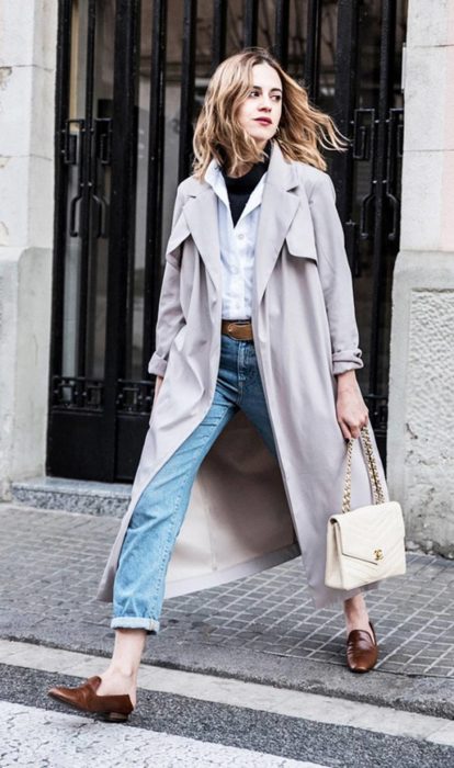 Chica usando mocasines con gabardina jeans y blusa de vestir blanca 