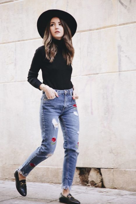 Chica usando mocasines con jeans rasgados y blusa negra 