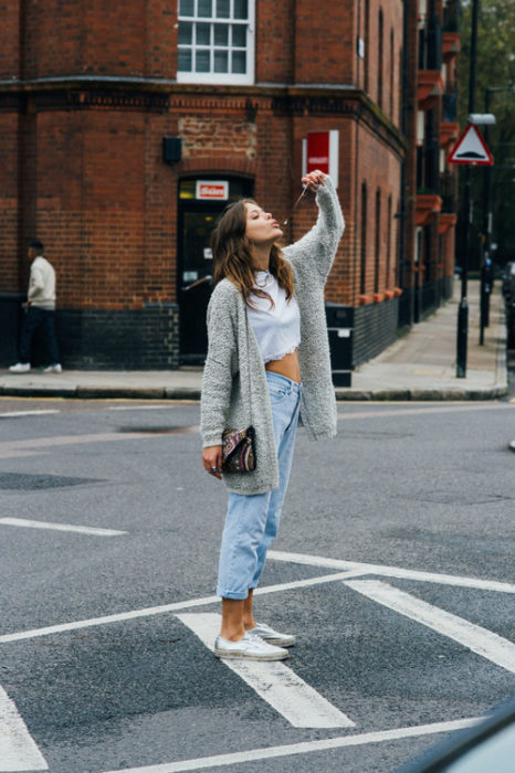 Chica usando unos mom jeans tenis y suéter gris 