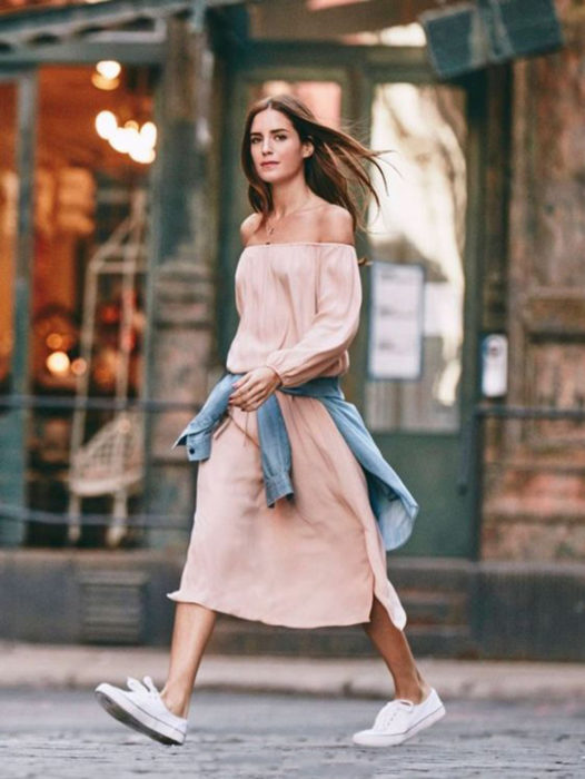 Chica usando un maxi vestido de color rosa palo y chaqueta de mezclilla atada a la cintura 