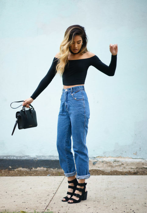 Chica usando unos pantalones de corte alto y blusa negra con choker 