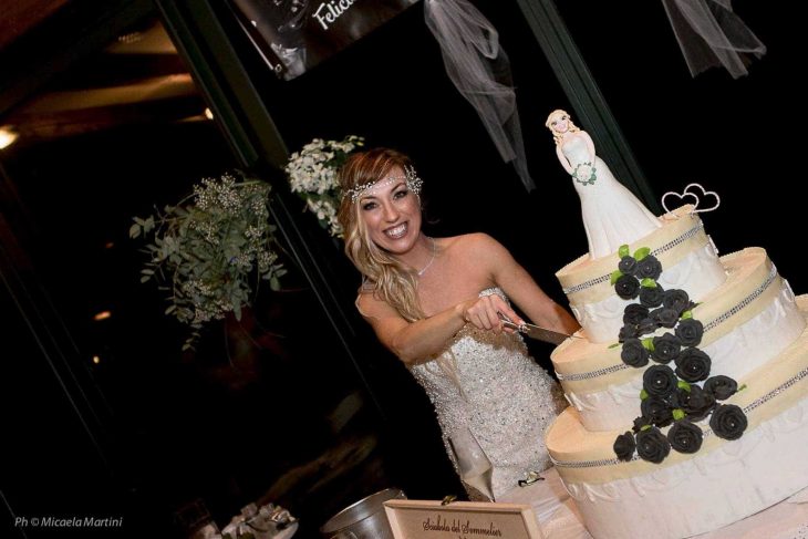 mujer con vestido de novia cortando pastel