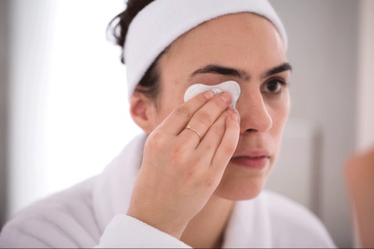 Chica desmaquillando sus ojos con aceite 