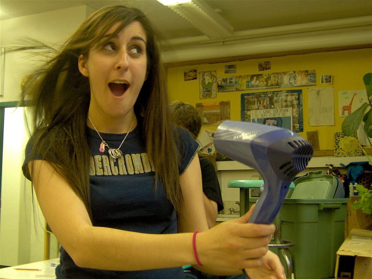 chica jugando con una secadora de cabello 