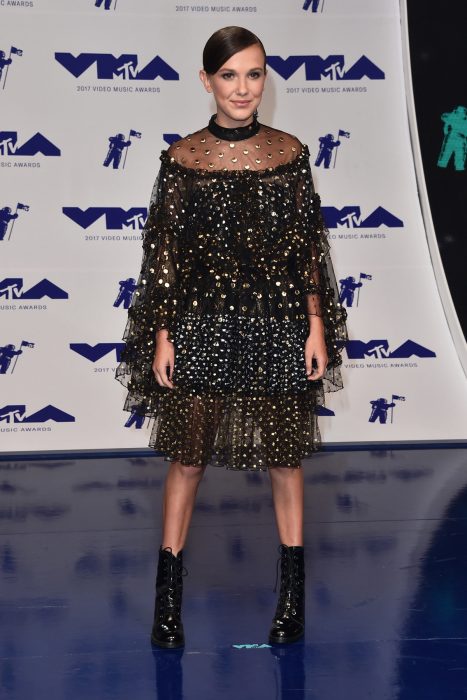 Millie Bobby Brown usando un vestido negro con estoperoles dorados