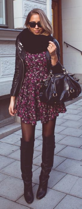 Chica usando un vestido con estampado floral botas y chaqueta negra 