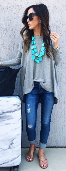 Chica usando una blusa gris con un collar color azul 