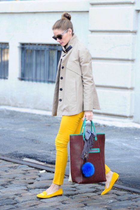 Chica usando un pantalón y zapatos amarillos un trench coat y una bolsa color café