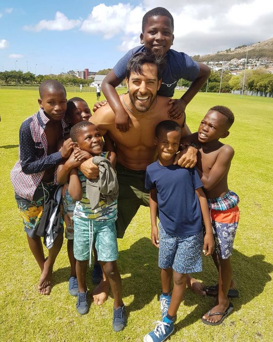 hombre jugando con niños al fútbol 