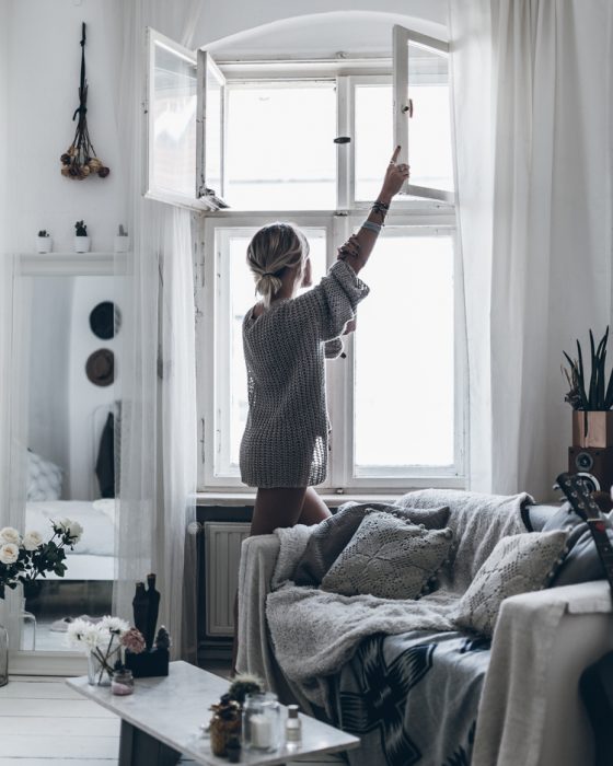 chica abriendo la ventanas de su departamento