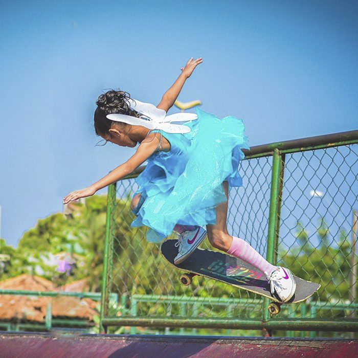 niña con vestido y alas en patineta 