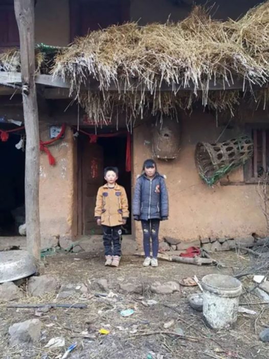 Niño que camina bajo la nive para poder llegar a la escuela parado junto a su hermana 