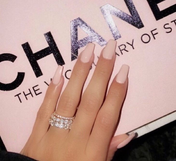 Uñas de color rosa sobre una caja de Chanel