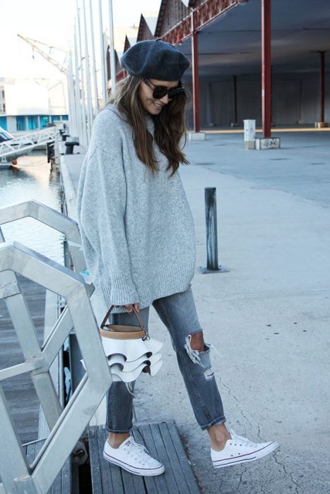 chica con pantalones desgarrados sudadera extra grande gris boina gris tenis converse blancos