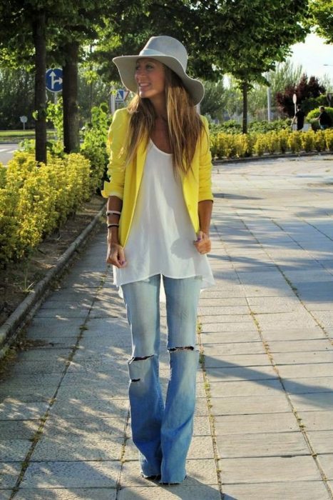 chica con blusa blanca sueter amarillo y pantalones de mezclilla rotos