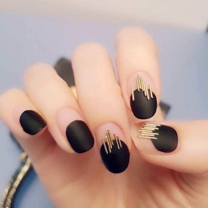 manicura de uñas negras con piedras doradas