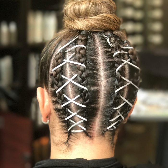 Chica usando unas corset braides en la nuca y que terminan en un bun alto 