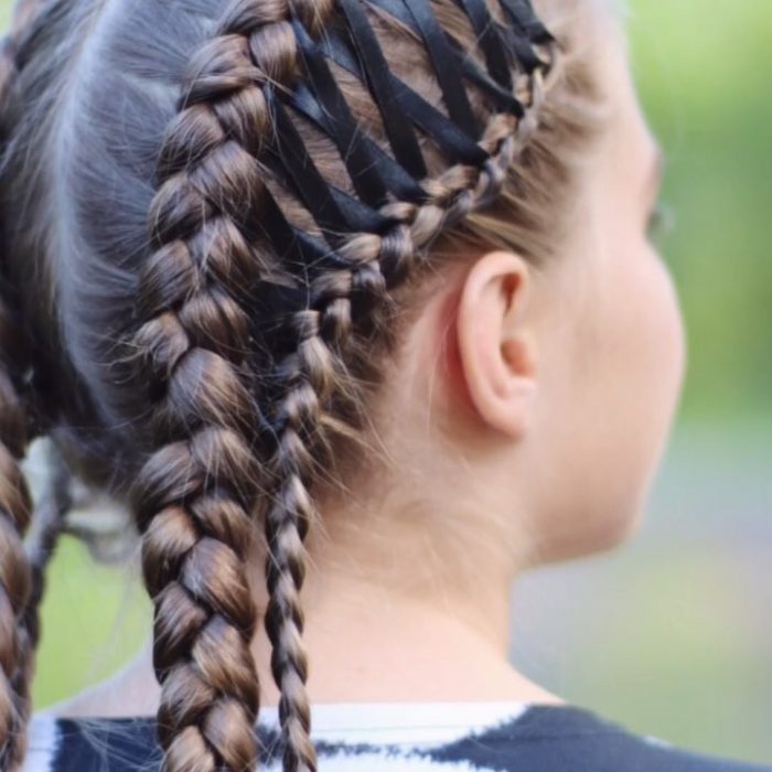 Chica usando unas trenzas de corset con un listón en color negro que las entrelaza 