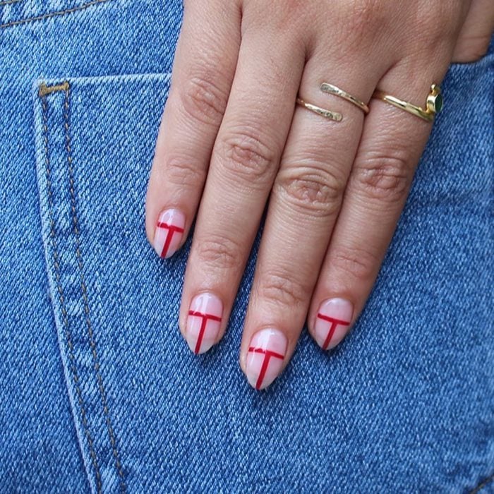 Uñas de almendra en tonos naturales con unas líneas de color rojo