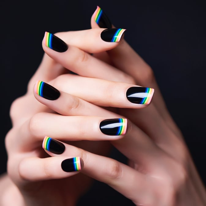 Diseño de uñas en color negro con líneas que simulan el arcoíris 