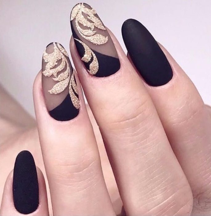 Uñas de stilletto con diseño de color negro con toques dorados