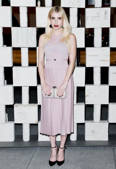 Emma Roberts caminando por la calle mientras usa un vestido color rosa 