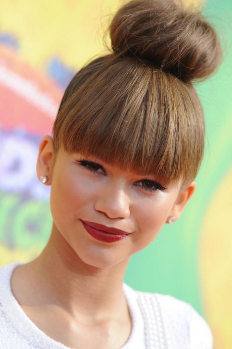 Zendaya usando el cabello en un moño con flequillo 