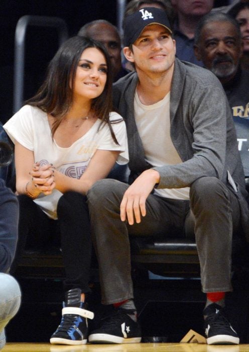 Mila kunis y Ashton Kutcher viendo un juego de baloncesto 