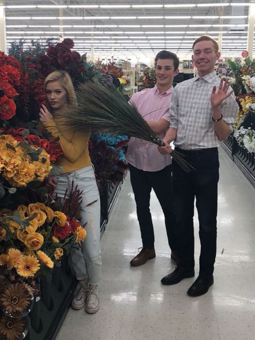 Chica recargada sobre flores sinteticas durante una sesión de fotos 