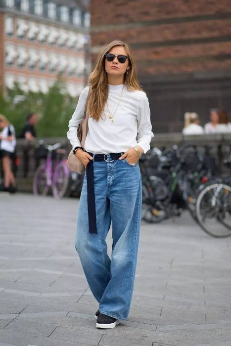 Chica usando unos jeans acampanados y una camisa blanca