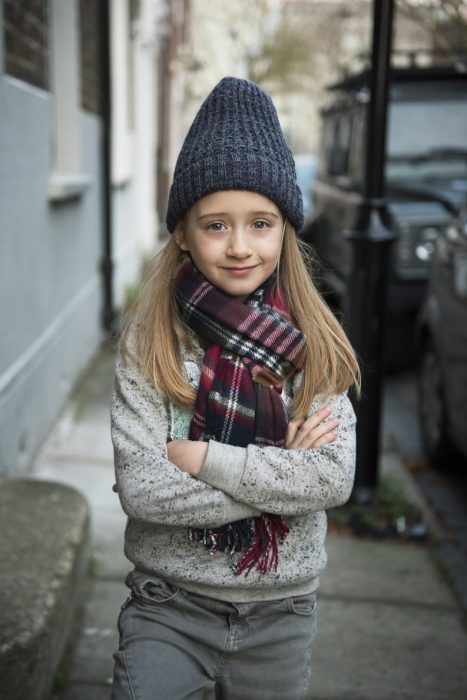 Niña que quiere ser modelo de Zara Boys posando con una bufanda sueter y pantalón de la marca 