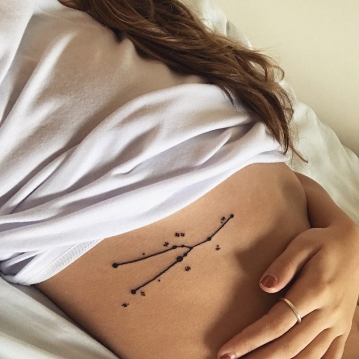 Chica con una constelación de estrellas tatuadas en las costillas 