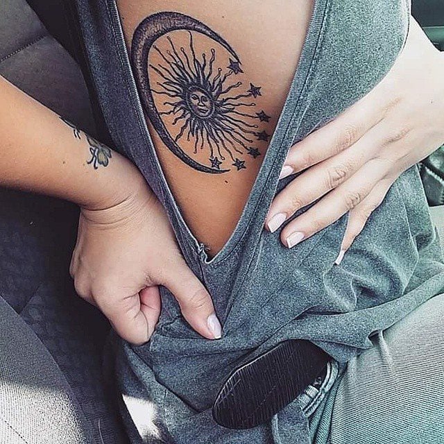Chica con un tatuaje del sol la luna y las estrellas tatuado en las costillas 