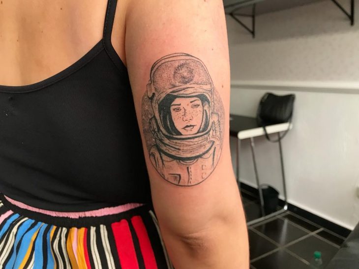 Chica con el tatuaje de una astronauta en su brazo 