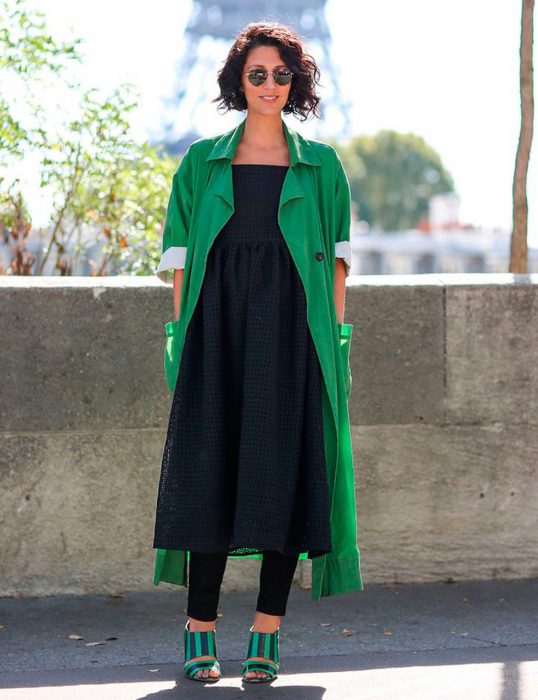 Chica usando un vestido sobre vaqueros mientras camina por la calle 