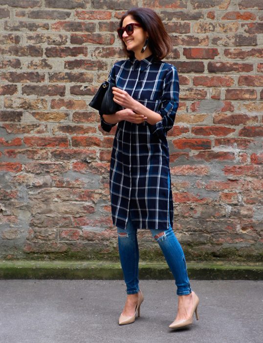 Chica usando un vestido sobre vaqueros mientras camina por la calle 