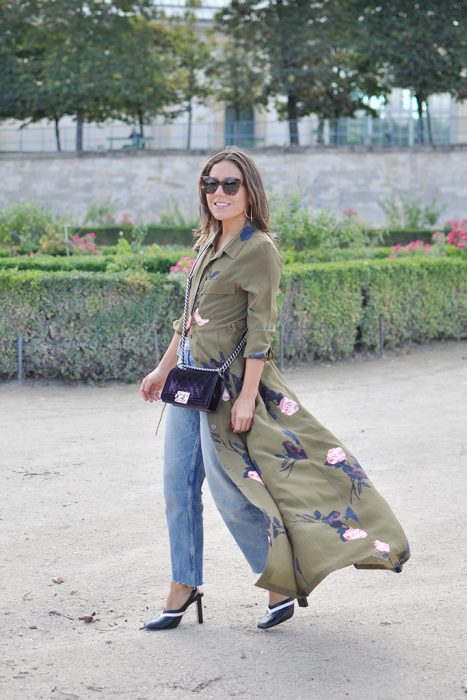 Chica usando un vestido sobre vaqueros mientras camina por la calle 