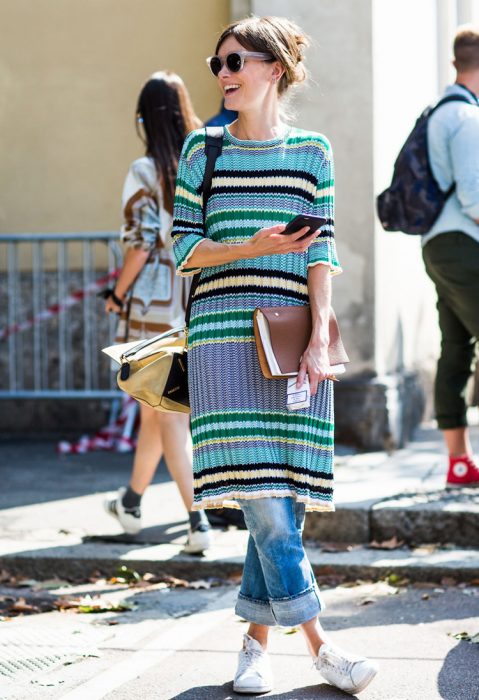 Chica usando un vestido sobre vaqueros mientras camina por la calle 