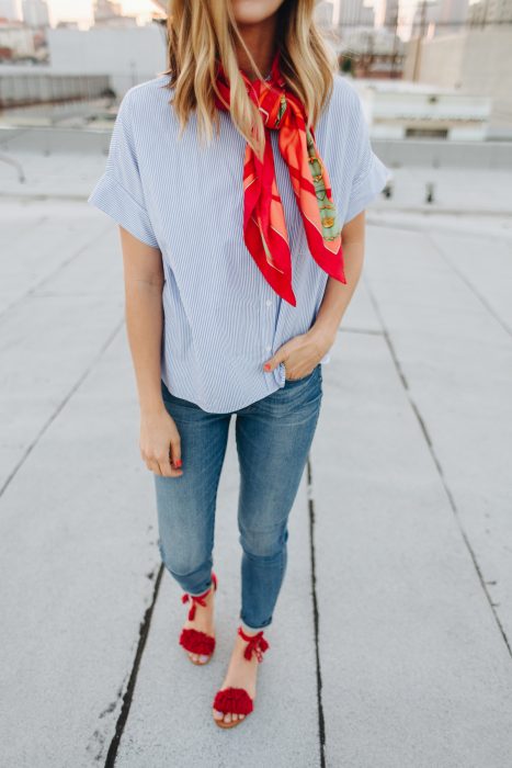 Chica usando un pañuelo rojo sobre el cuello mientras viste de mezclilla y unos zapatos rojos 