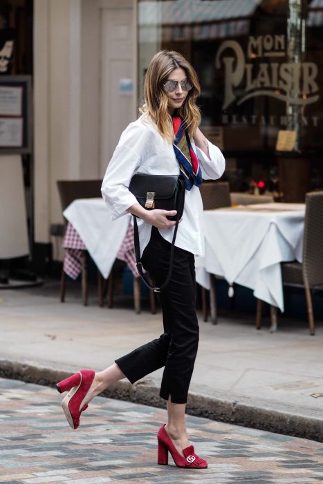 Chica caminando por la calle usando un atuendo blanco y negro con unos zapatos cuadrados de color rojo 