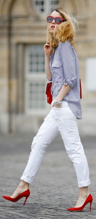 Chica caminando por las calles mientras usa un pantalón blanco, zapatos rojos y blusa color azul 