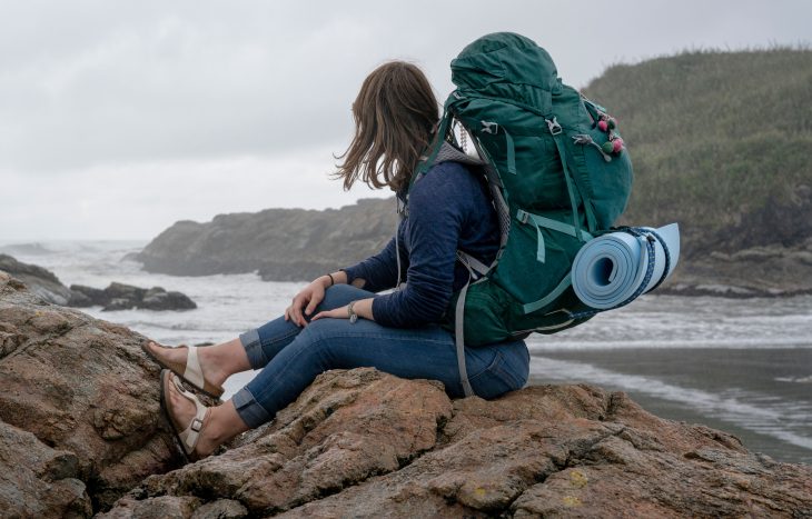 chica viajera con mochila de montaña y sandalias 