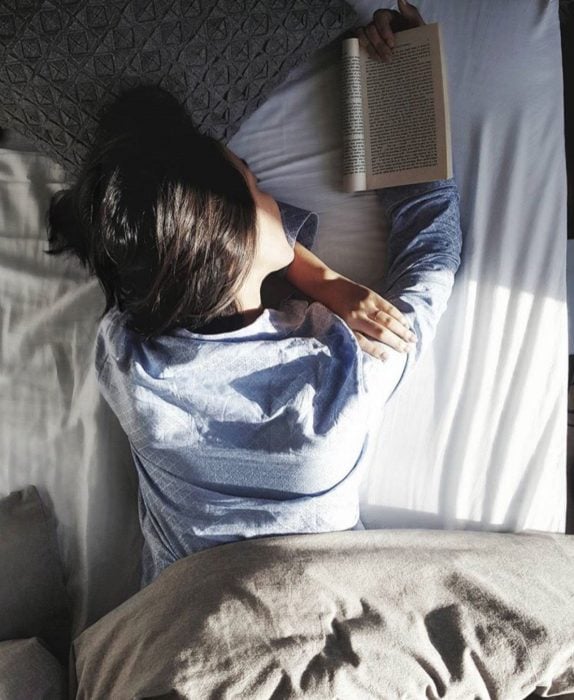 chica acostada en cama leyendo