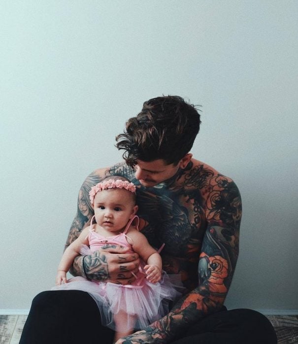 chico con tatuajes cargando a su hija 