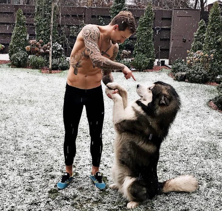 chico jugando con un perro bajo la nieve